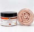 A jar of whipped foaming sugar soap scrub labeled 'Harvest Latte' with a black lid, shown next to an open clear jar displaying the swirled pale pink scrub with dark red specks, on a white background.