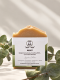 A single bar of handmade cold process soap labeled 'RESET' by Soap appeal, styled with green eucalyptus leaves on a light beige background with soft shadows.