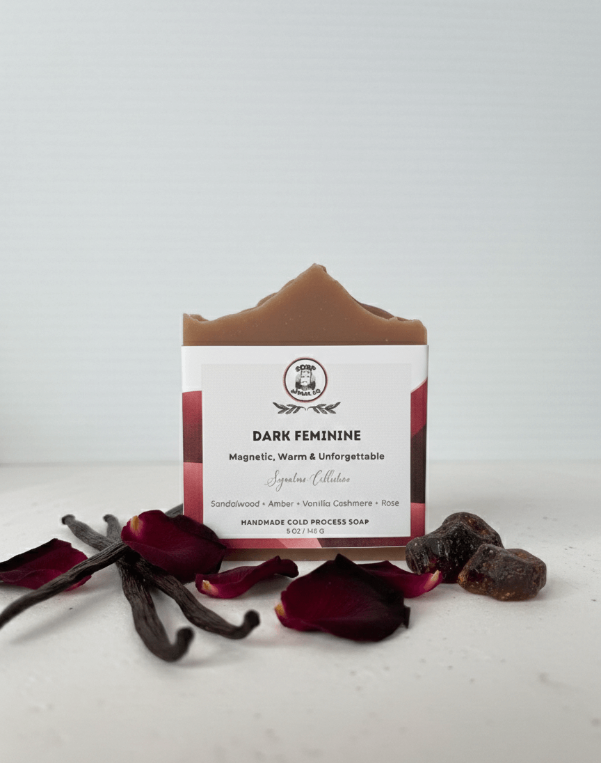 Bar of soap with a label on a white background, surrounded by vanilla beans and rose petals.
