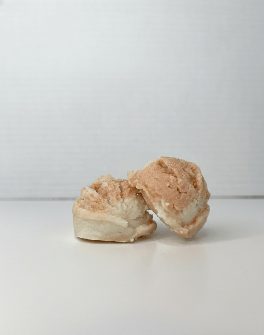 Two white and dusty rose tallow truffles on a white background