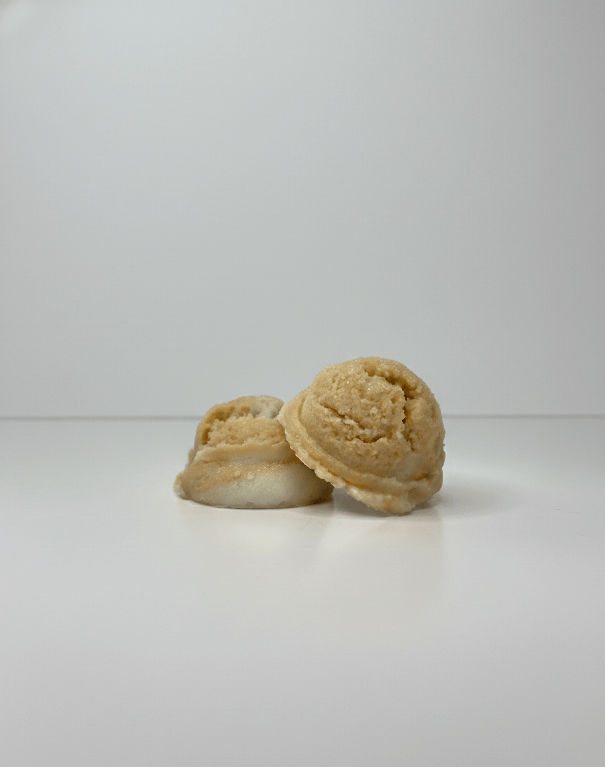 Two orange/gold-colored tallow truffles on a white background