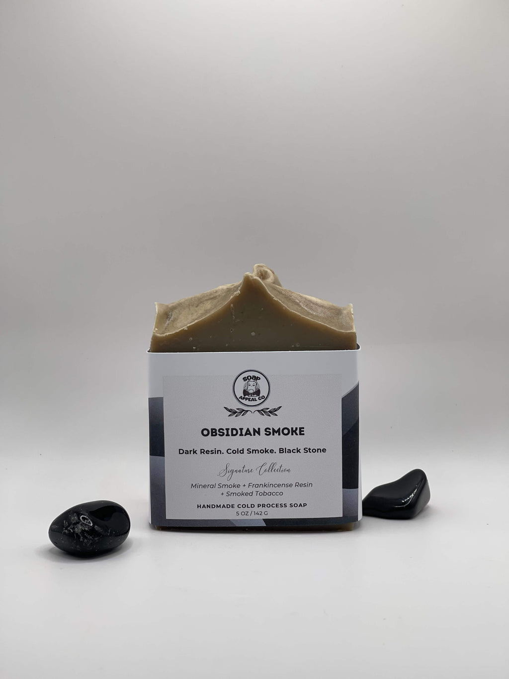 Grey soap with two black stones on a white background