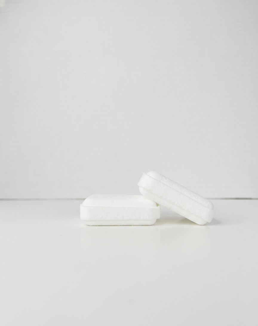 Two white shower steamers on a light gray background