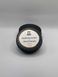 Black container of grass fed tallow and zinc sun block on a gray background