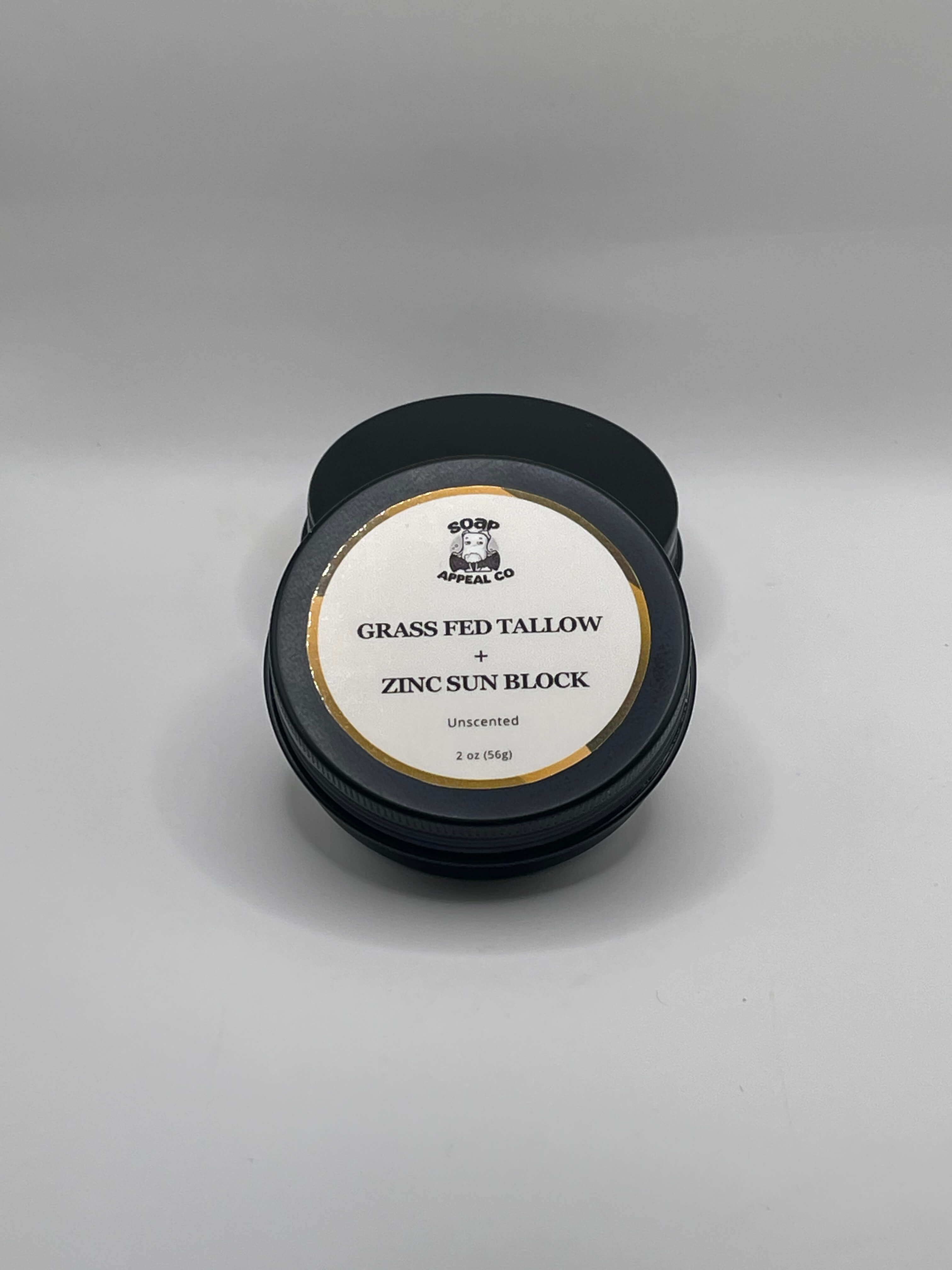 Black container of grass fed tallow and zinc sun block on a gray background